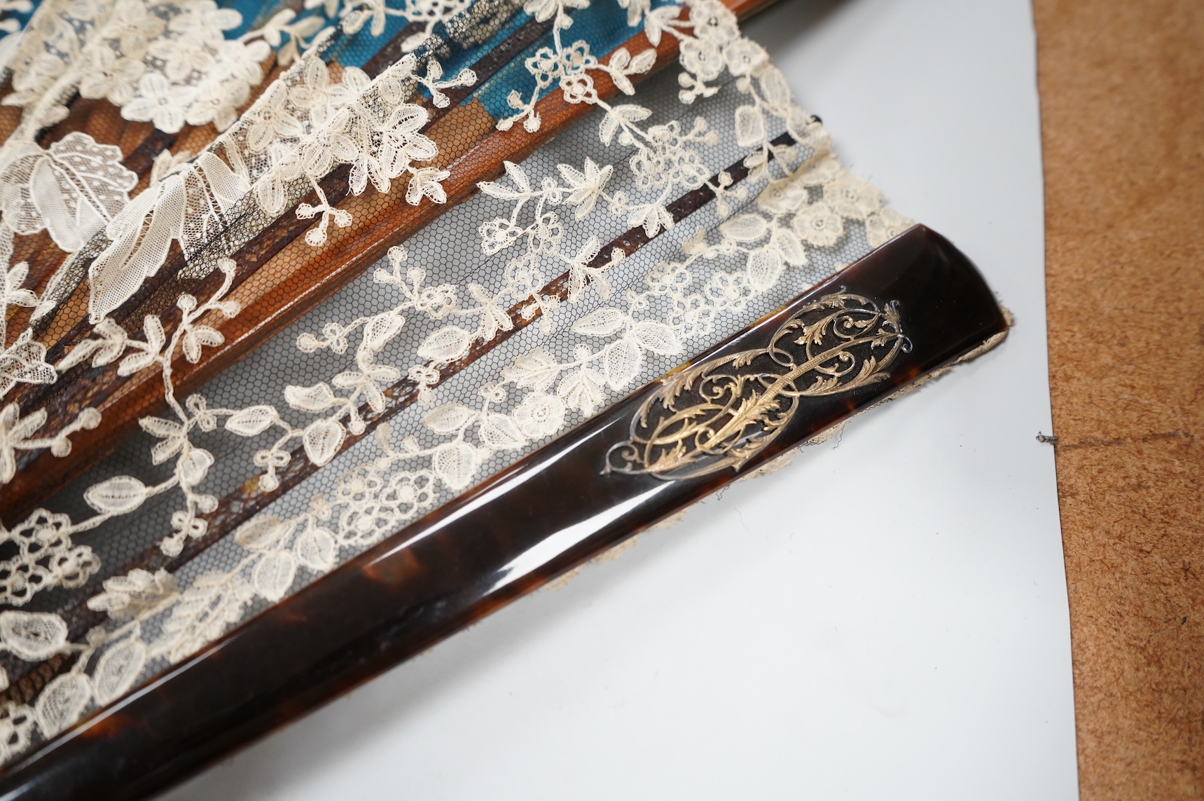 A gold mounted lace and hand painted fan and three others to include a lacquered example, one cased